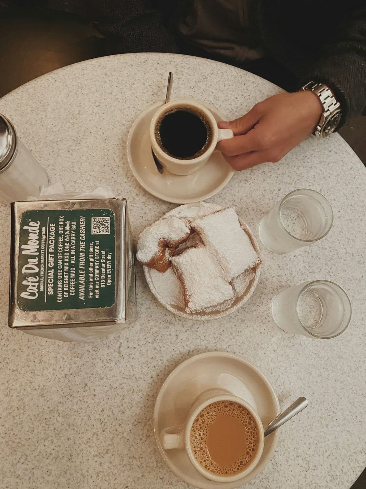 Beignets dusted with powdered sugar next to a cafe au lait in New Orleans