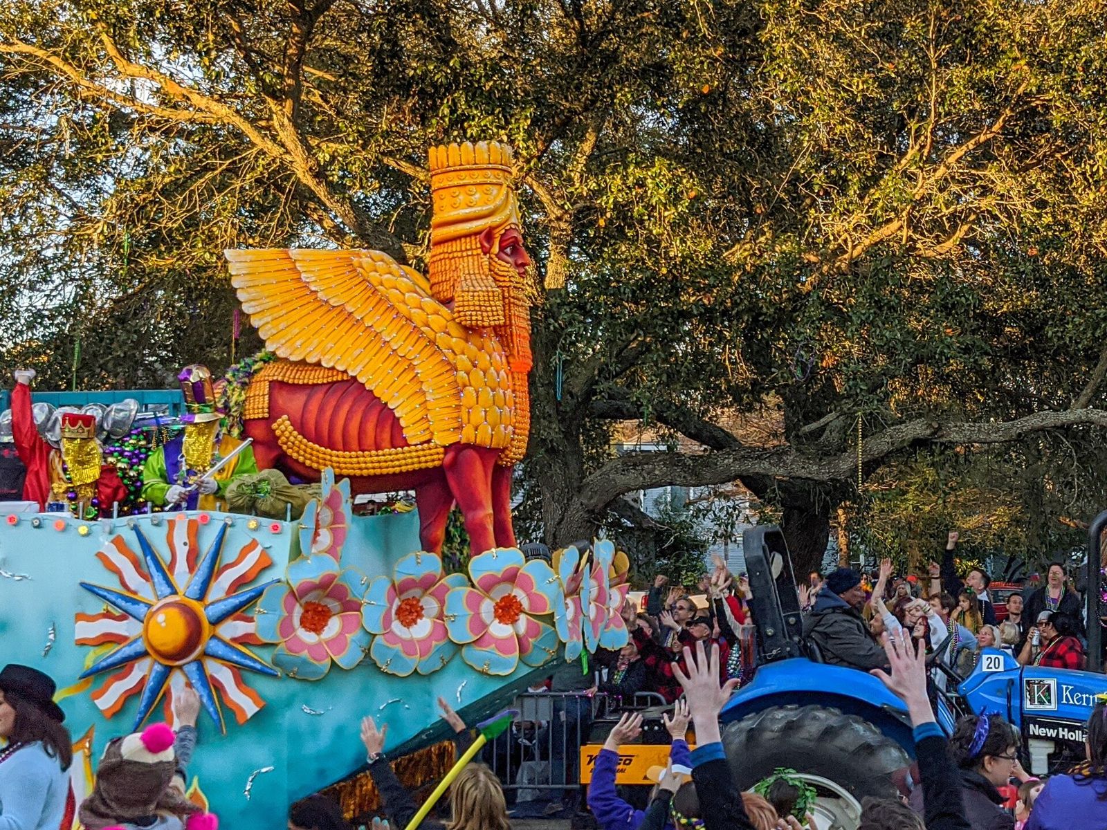 A huge golden winged Lamassu sculpture on an Endymion float rolls under live oaks as the crowd reaches for throws