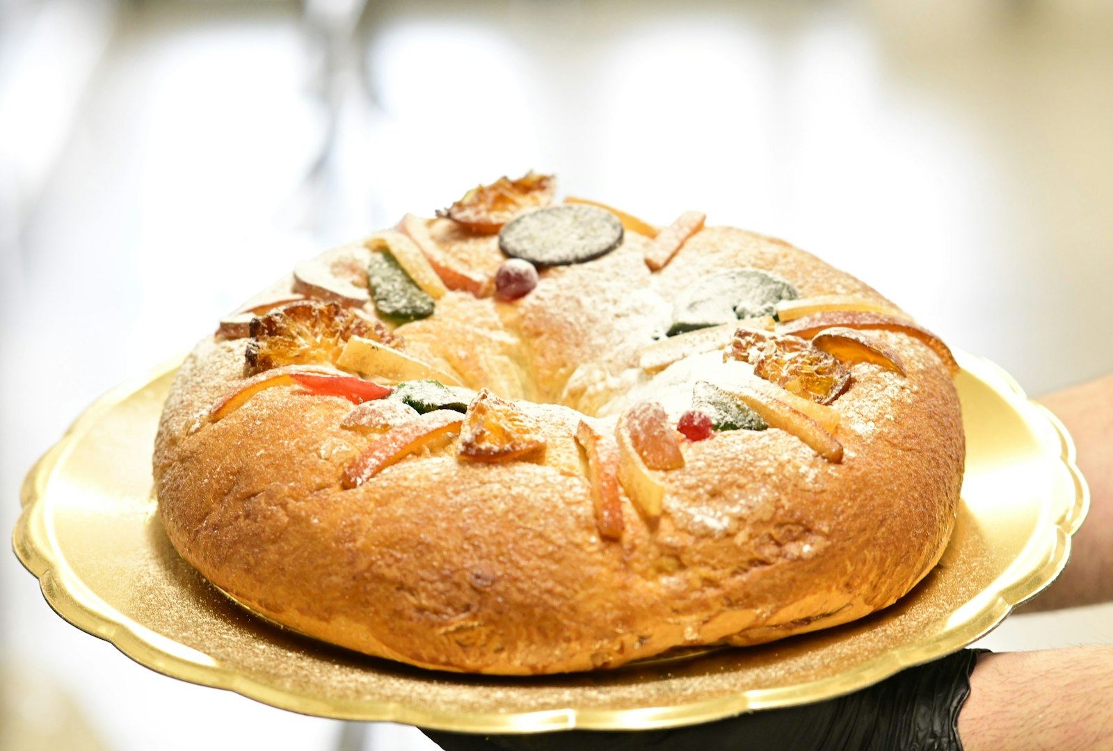 Round king cake topped with candied fruit and powdered sugar